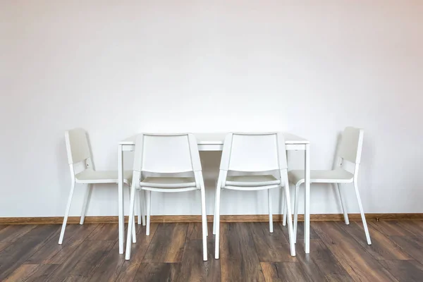 white wooden chairs with a table against the background of a white wall in the interior