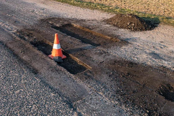 Cone de perigo de tráfego laranja branco na reparação de estradas de asfalto — Fotografia de Stock