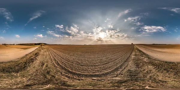 Panorama esférico sin costuras completo 360 grados ángulo de visión cerca de carretera de grava entre los campos de pradera en la puesta de sol de la noche de primavera con nubes impresionantes en proyección equirectangular, contenido de realidad virtual VR AR — Foto de Stock