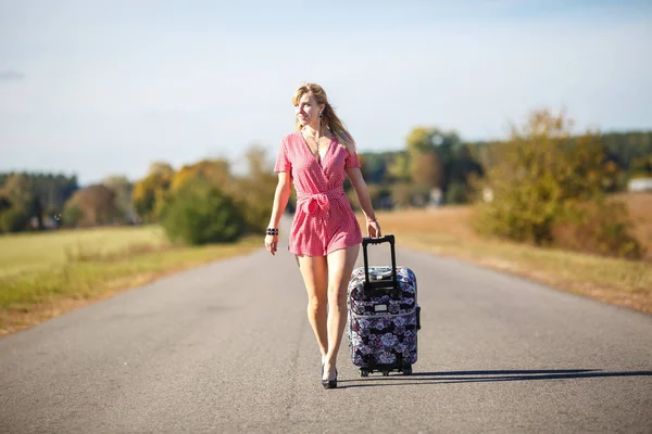 Jonge vrouw liften op een weg op de velden — Stockfoto