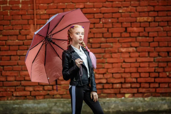 Portrait rapproché de petite fille élégante enfant avec un parapluie sous la pluie près du mur de briques rouges comme arrière-plan — Photo
