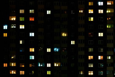 Çok katlı bir binanın penceresinde gece vakti ışık çarpması. Büyük bir şehirde hayat