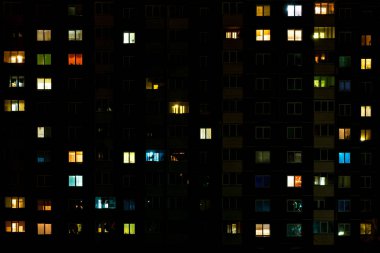 Çok katlı bir binanın penceresinde gece vakti ışık çarpması. Büyük bir şehirde hayat