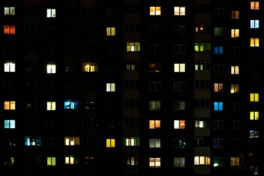 Çok katlı bir binanın penceresinde gece vakti ışık çarpması. Büyük bir şehirde hayat