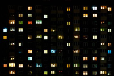 Çok katlı bir binanın penceresinde gece vakti ışık çarpması. Büyük bir şehirde hayat
