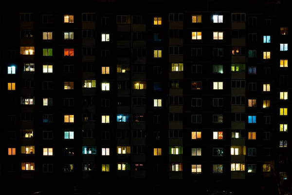 在一幢多层建筑物的窗户上，夜幕降临。大城市的生活 — 图库照片