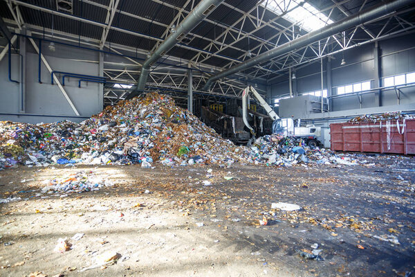 GRODNO, BELARUS - MAY 2018: Excavator on primary sorting of garbage at waste processing plant. Separate garbage collection. Recycling and storage of waste for further disposal. 