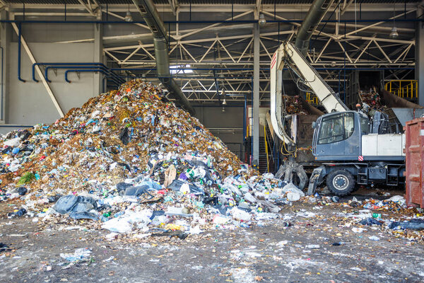 GRODNO, BELARUS - MAY 2018: Excavator on primary sorting of garbage at waste processing plant. Separate garbage collection. Recycling and storage of waste for further disposal. 