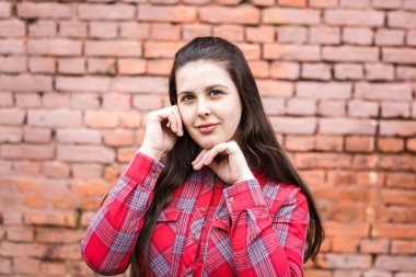 arka plan olarak pembe tuğla duvara yakın kırmızı ekose gömlek büyük artı boyutu güzel şık çocuk kız yakın portre