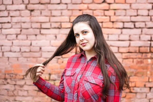 Portrait rapproché de grande plus la taille belle fille élégante enfant en chemise à carreaux rouge près du mur de briques roses comme fond — Photo