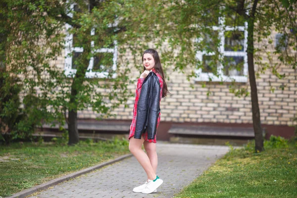 Close up portrait of big plus size beautiful stylish kid girl with leather jacket  and red plaid shirt near brick building in urban street as background — Stock Photo, Image