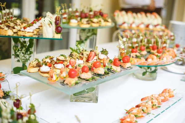 Catering. Comida fuera del lugar. Mesa buffet con varios canapés, sándwiches, hamburguesas y aperitivos . — Foto de Stock