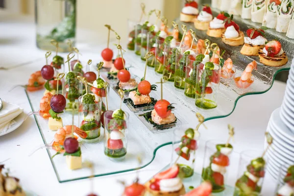 Catering. Comida fuera del lugar. Mesa buffet con varios canapés, sándwiches, hamburguesas y aperitivos . — Foto de Stock