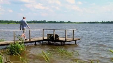 adam rüzgarlı havalarda gölde bir iskelede yürüyor