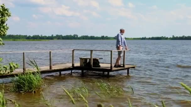 Man Staat Een Pier Aan Het Meer Winderig Weer — Stockvideo