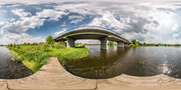 Completo sin costura esférica hdri panorama 360 grados ángulo de vista en el muelle de madera de la orilla de ancho río cerca de puente en día soleado con nubes en proyección equirectangular, contenido VR AR listo —  Fotos de Stock