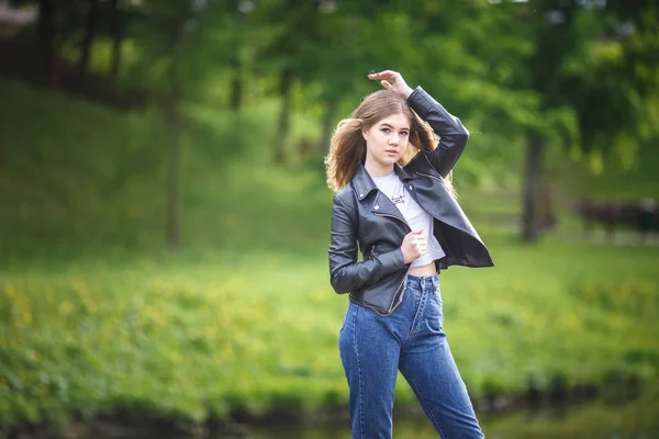 Retrato de niña hermosa y elegante en el parque de la ciudad en el fondo verde del bosque — Foto de Stock