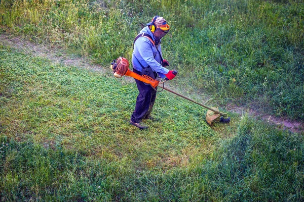 Översta vyn lawnmover man arbetare skär torrt gräs med gräsklippare. — Stockfoto