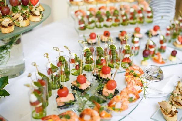 Catering. Comida fuera del lugar. Mesa buffet con varios canapés, sándwiches, hamburguesas y aperitivos . — Foto de Stock