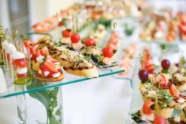 Catering. Comida fuera del lugar. Mesa buffet con varios canapés, sándwiches, hamburguesas y aperitivos . — Foto de Stock