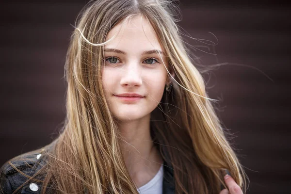 Retrato de cerca de la pequeña niña hermosa y elegante con el pelo largo que fluye contra una pared de rayas marrón — Foto de Stock