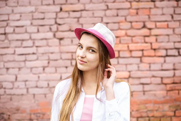 Primer plano retrato de hermosa niña con estilo en el sombrero cerca de la pared de ladrillo rosa como fondo — Foto de Stock