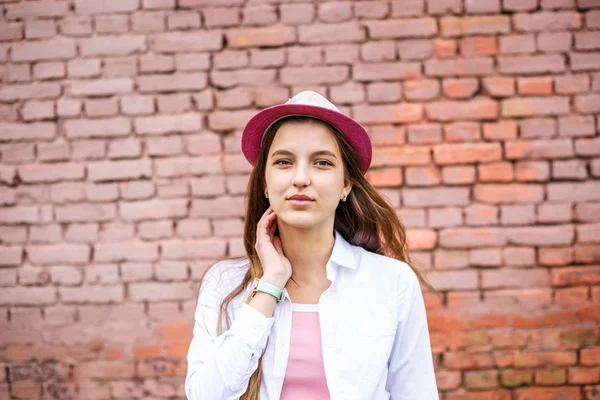 Primer plano retrato de hermosa niña con estilo en el sombrero cerca de la pared de ladrillo rosa como fondo — Foto de Stock