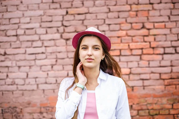 Close up portrait of beautiful stylish kid girl in hat near pink brick wall as background — Stock Photo, Image
