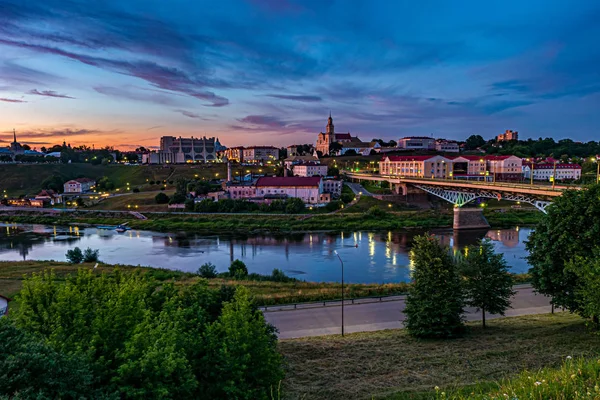 Panoramautsikt på kvällen i gamla stan på stranden av wide River med kvällen fluffiga lockiga rullande Cirrostratus moln och blå violett röd solnedgång himmel som bakgrund — Stockfoto