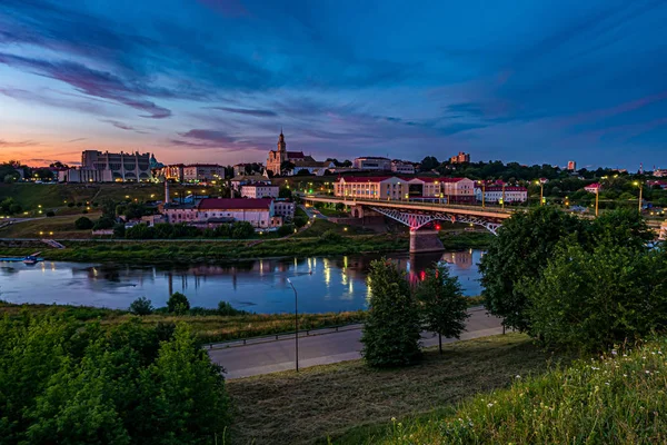Panoramablick am Abend in der Altstadt am Ufer des breiten Flusses mit abends flauschig lockig rollenden Schleierwolken und blauviolett-rotem Sonnenuntergangshimmel als Hintergrund — Stockfoto