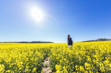 yaz aylarında çiçekli kolza alanında mavi elbise genç mutlu güzel büyük beden model kız. Beni takip et konsepti
