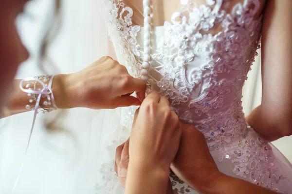 Ung flicka brud i bröllopsklänning väntar på brudgummen. Flickvän hjälper till att fästa en klänning — Stockfoto