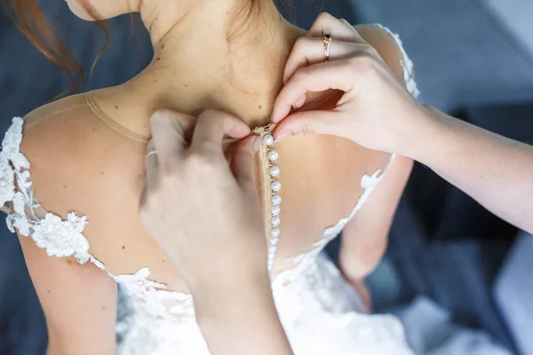 young girl bride in wedding dress is waiting for the groom. girlfriend helps to fasten a dress