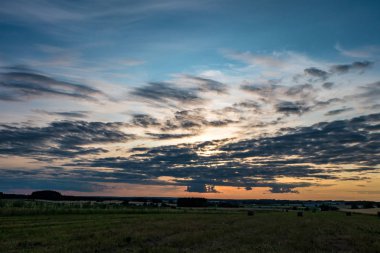 Güneş ayarı ile akşam kabarık kıvırcık Rolling Altocumulus Altostratus bulutlar ile mavi gökyüzü arka plan. İyi rüzgarlı hava