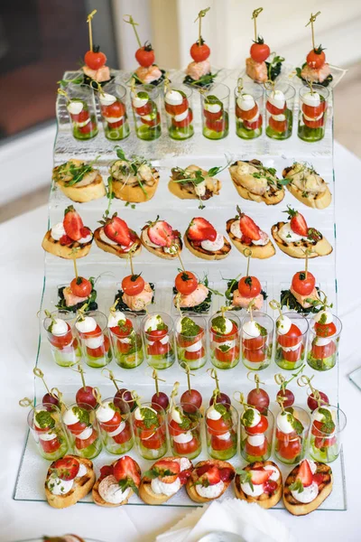 Mesa de cristal buffet con varios canapés, sándwiches, hamburguesas — Foto de Stock