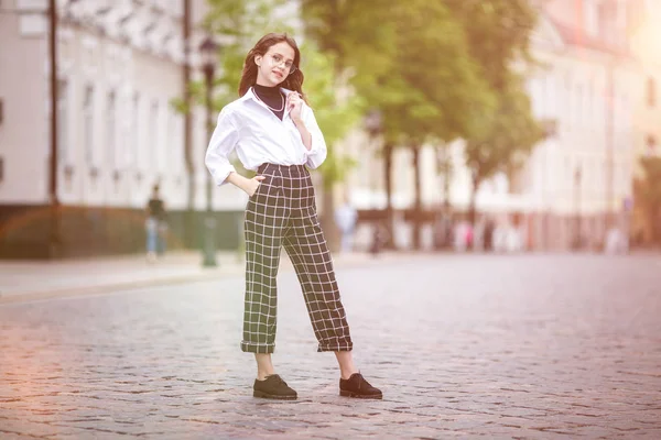 Portræt af lille smuk stilfuld pige med solbriller og korte plaid bukser i byen urban street - Stock-foto