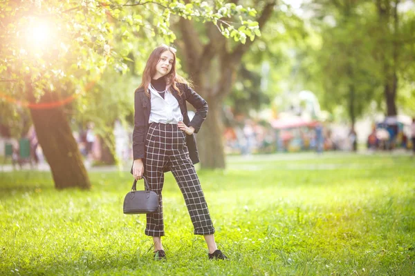 小美丽的时尚女孩的肖像与太阳镜和短格子裤在城市公园的绿色森林背景 — 图库照片