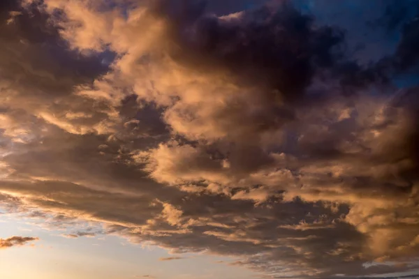 Blauroter Himmelshintergrund mit abends flauschigen lockigen Wolken mit untergehender Sonne. Gutes windiges Wetter — Stockfoto