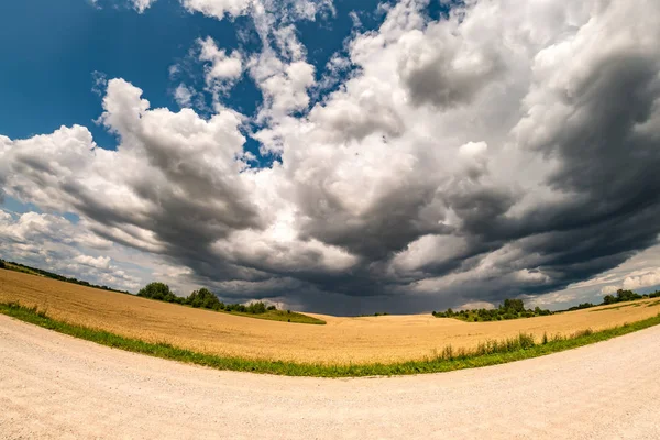 Panorama hdr sur route de gravier entre les champs en soirée avec des nuages noirs impressionnants avant la tempête — Photo