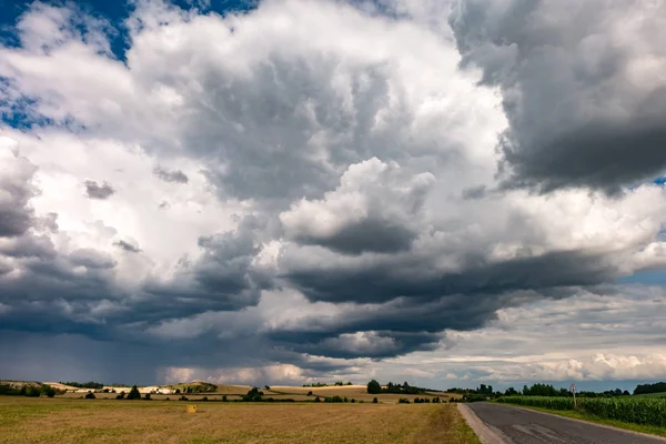 Panorama hdr na estrada de cascalho entre os campos à noite com nuvens negras impressionantes antes antes da tempestade — Fotografia de Stock