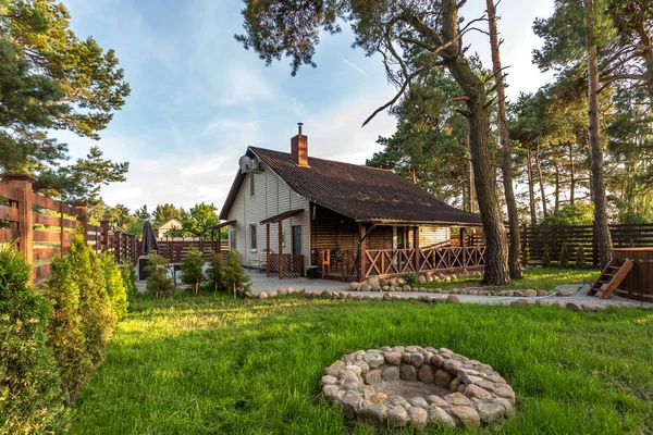 Moderna casa de campo ecológica en un bosque de pinos al atardecer — Foto de Stock