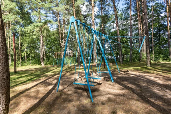 Качели и горизонтальные полосы на детской площадке в сосновом лесу — стоковое фото