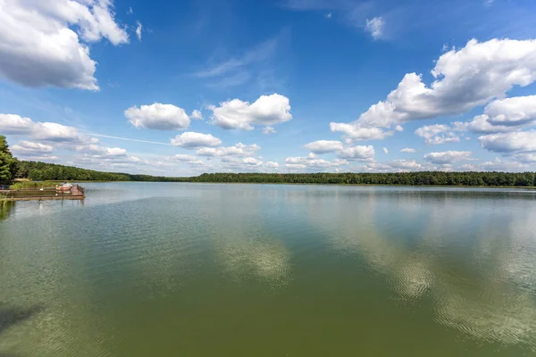Molo na břehu velkého jezera v letním dni s nádherními mraky. Nebeský odraz — Stock fotografie