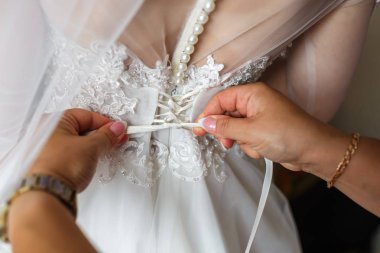 gelinlikli genç kız gelin damadı bekliyor. kız arkadaşı bir elbise bağlamak için yardımcı olur