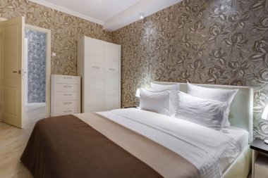 Minsk, Belarus - Eylül 2019: Kahverengi renkli daireler ve gece lambalarıyla modern lüks yatak odasının iç mekanı.