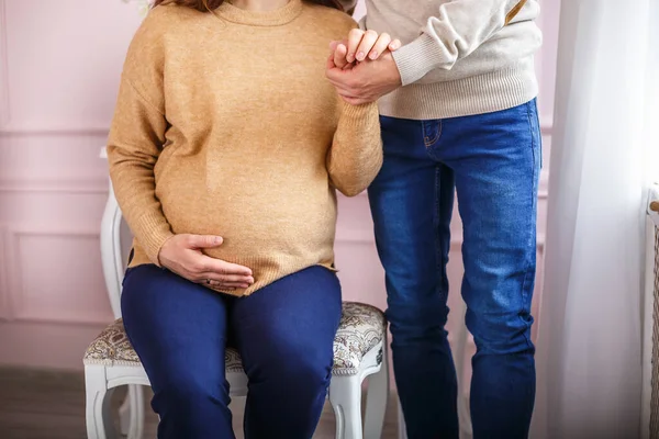 Stivaletti lavorati a maglia nelle mani di una donna incinta accanto al marito. aspettando un miracolo — Foto Stock