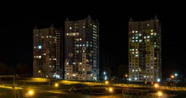 Çok katlı bir binanın penceresinde gece vakti ışık çarpması. Büyük bir şehirde hayat