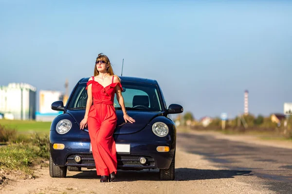 빨간 색옷을 입고 차 근처에서 선글라스를 쓴 행복 한 젊은 모델 소녀 — 스톡 사진