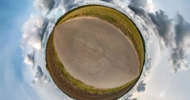 Uzayın kıvrımlı küçük bir gezegen dönüşümü. Soyut bükülme ve güneşli bir günde tarlalar arasında güzel bulutlarla uçan tam panorama. İHA havalanıyor ve dönüyor