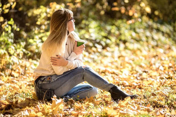 Meisje zit en ontspannen op de grond in de herfst bos met coff — Stockfoto